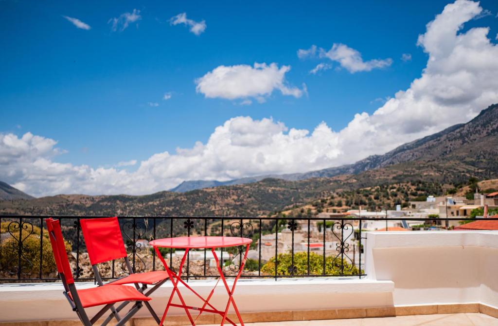 a red table and chairs on a balcony with mountains at Mitato Eagle's Nest Asfentamos in Níthavris