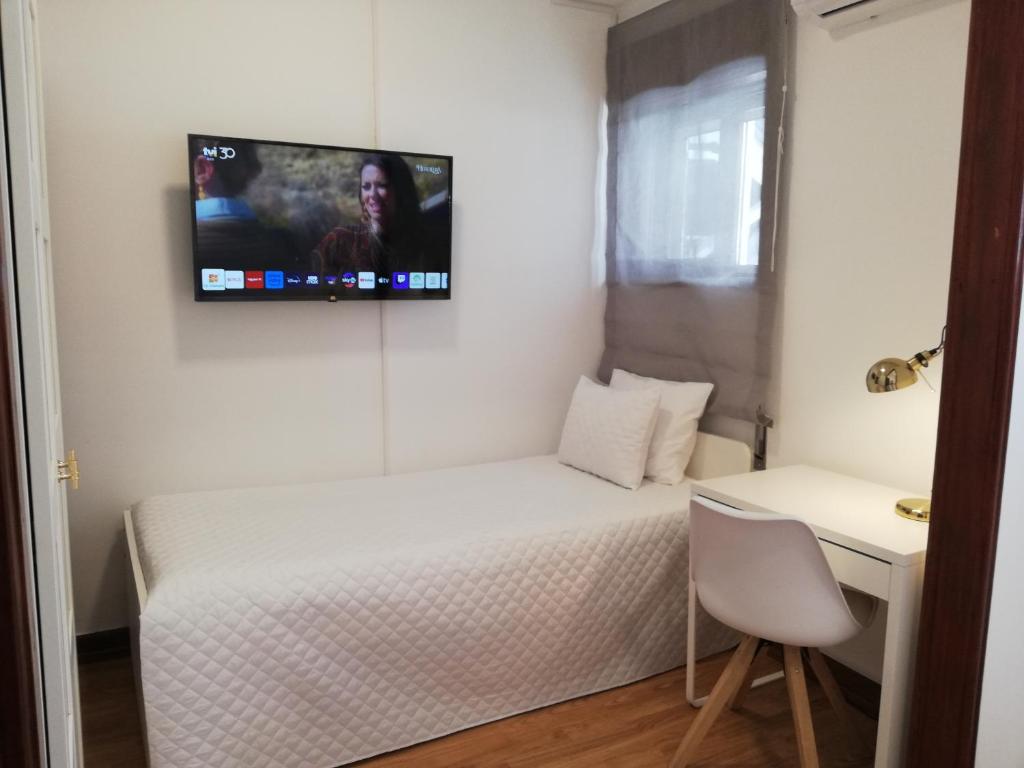 Kleines Zimmer mit einem Bett und einem TV an der Wand in der Unterkunft Buddies Charm House in Aveiro