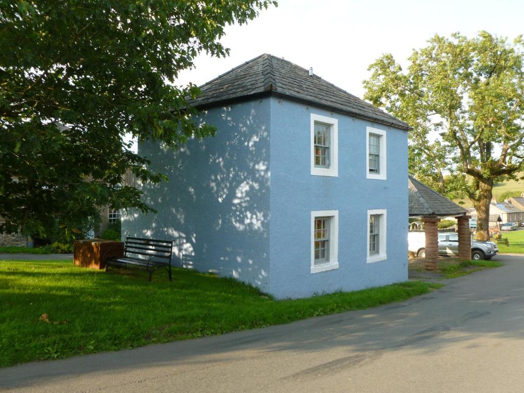 una casa azul con un banco en el césped en The Coach House, Hesket Newmarket en Hesket Newmarket