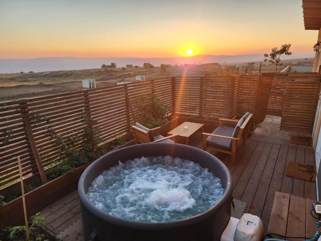a hot tub on a deck with a sunset in the background at בריאה אירוח בטבע in Sha'al