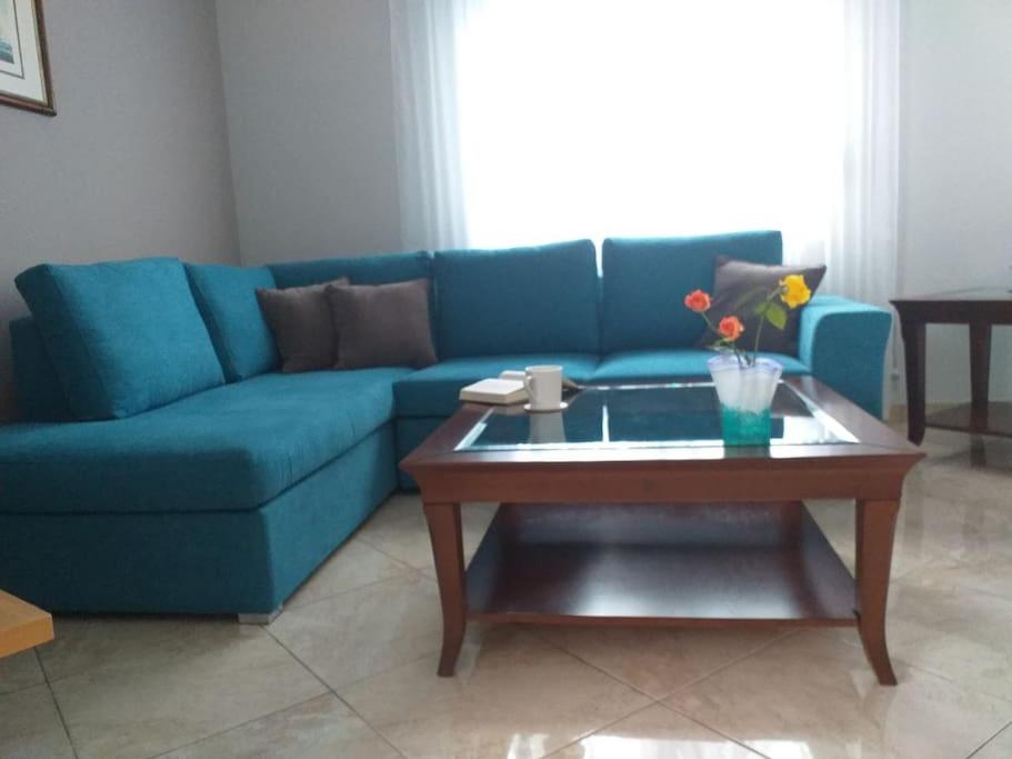 Sofá azul en la sala de estar con mesa de centro en Aggeliki's place detached home with yard/parking, en Volos