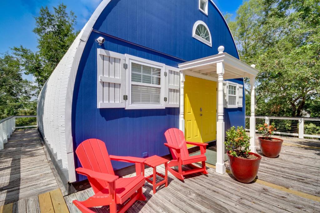 a blue and yellow tiny house with red chairs on a deck at Charming Bay St Louis Home Deck, on Canal! in Shoreline Park