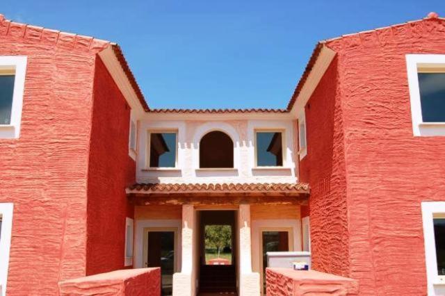 a large red brick building with a white window at La Cerbiatta Residence in Porto San Paolo