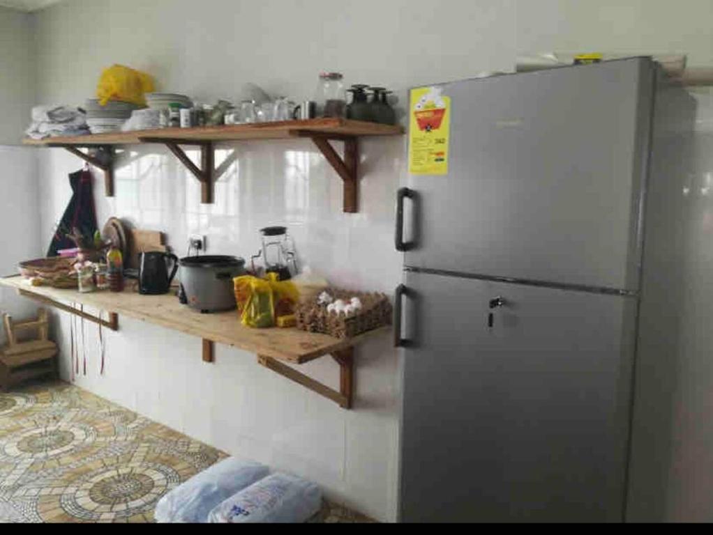 uma cozinha com um frigorífico de aço inoxidável e prateleiras de madeira em Anne’s Beach House em Nyanyanu