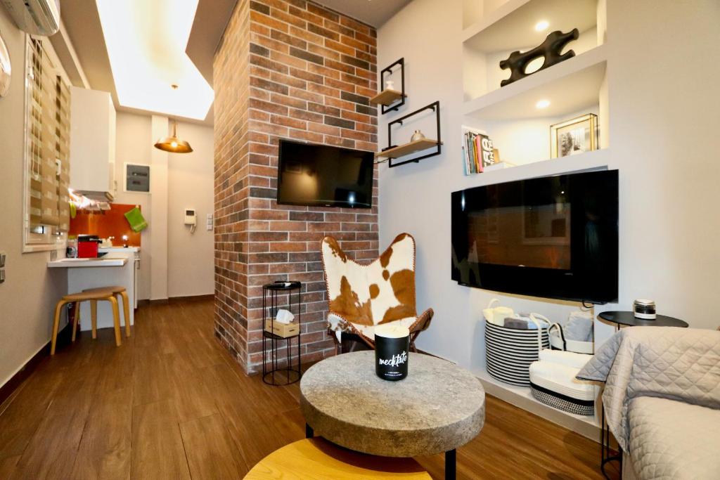 a living room with a brick fireplace and a tv at Modern Studio in Vibrant Kolonaki Area in Athens