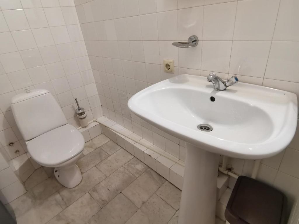 a white bathroom with a toilet and a sink at EUROPEAN Backpackers Hostel in Tbilisi City