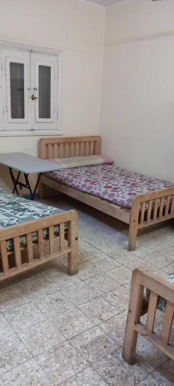 a room with two beds and a table and benches at طنطا أول طريق شوبر in Quḩāfah