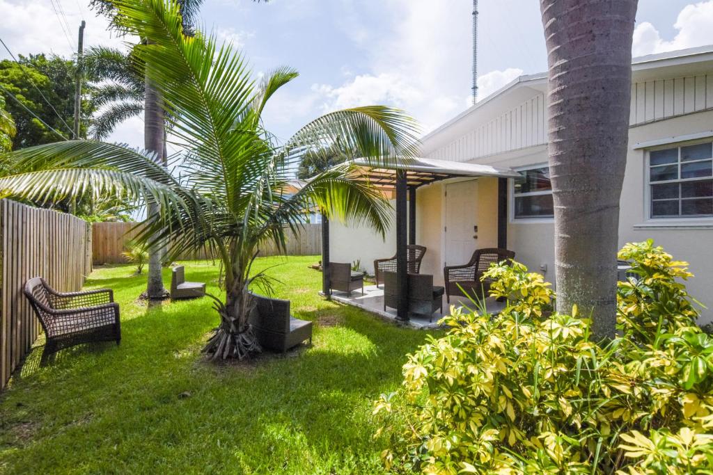 un patio con bancos y palmeras frente a una casa en Family-Friendly Miami Oasis with Patio and Yard!, en Miami Gardens