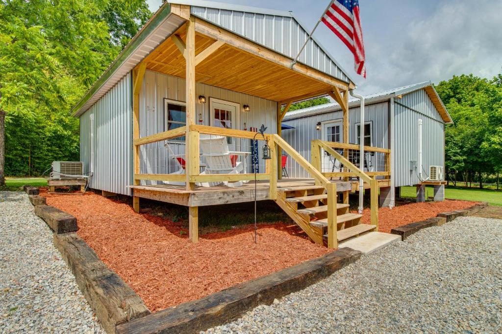 ein winziges Haus mit einer Veranda und einer Flagge in der Unterkunft Studio Cabin in Norfork about Half-Mi to White River! in Norfork