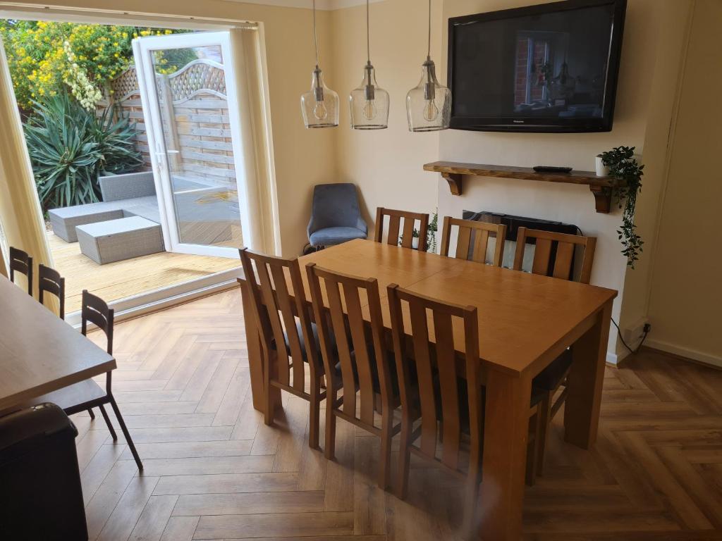 uma sala de jantar com uma mesa e cadeiras e uma televisão em Crabtree House em Moreton