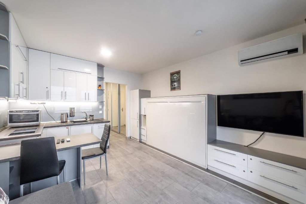 a kitchen with white cabinets and a large flat screen tv at Rezidencia pri Radnici in Košice