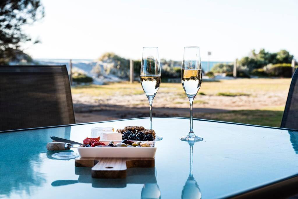 zwei Gläser Wein und ein Teller Essen auf dem Tisch in der Unterkunft Beachfront Escape in Port Adelaide