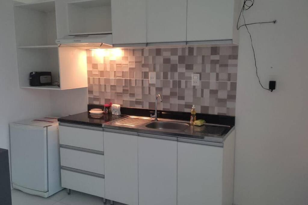 una cocina con armarios blancos y fregadero en Departamento en Villa Elisa. en Villa Elisa