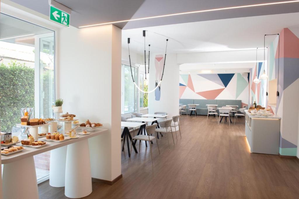 a restaurant with white walls and tables and chairs at Amarina Hotel in Marina di Pietrasanta