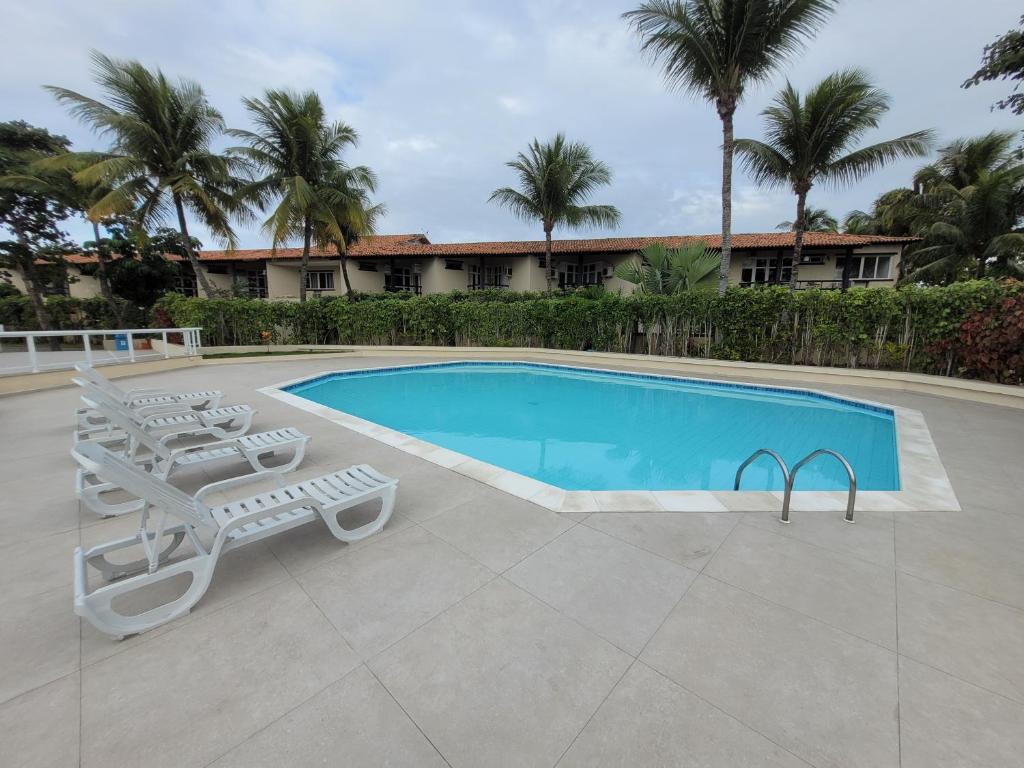 une piscine avec deux chaises et une table dans l'établissement Centro de Búzios 2 quartos, à Búzios