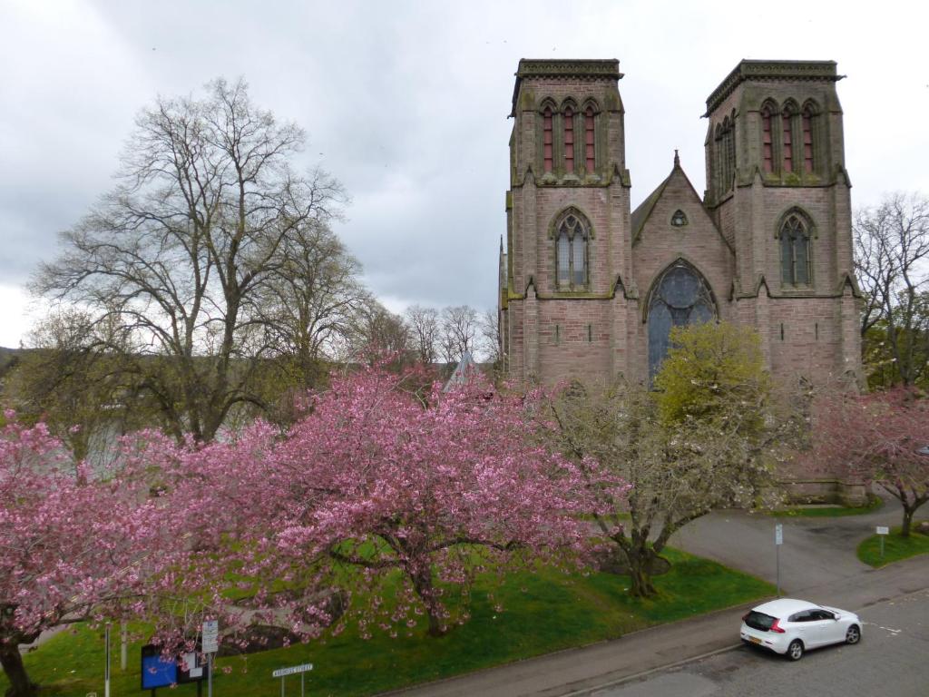 una vieja iglesia con un coche aparcado delante de él en Macdonald House en Inverness