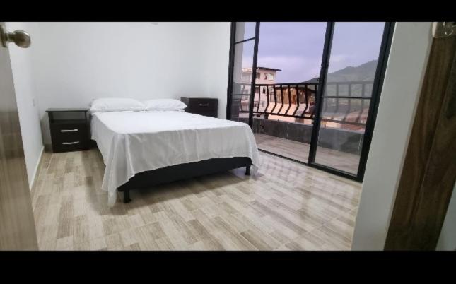 1 dormitorio con cama y ventana grande en Acogedor apartamento en la ciudad de las araucarias en Santa Rosa de Cabal