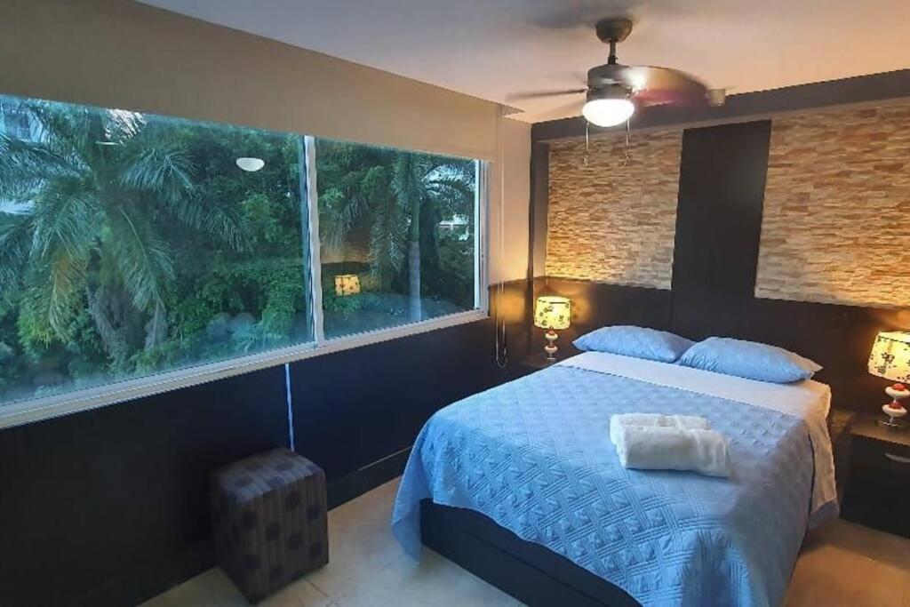 a bedroom with a bed and a large window at R.1108 Lindo aparta estudio equipado tipo ejecutivo. in Panama City