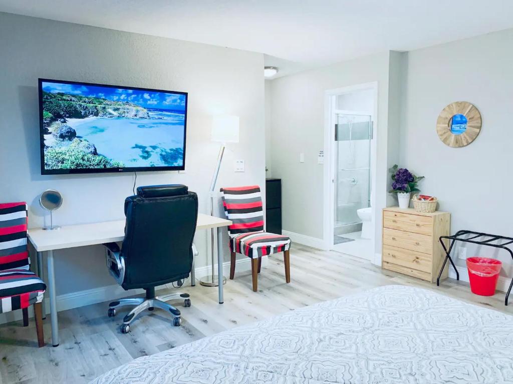 Habitación con escritorio, sillas y TV en la pared. en Brand new suite, 1mi to Meta, 3mi to Stanford, en East Palo Alto