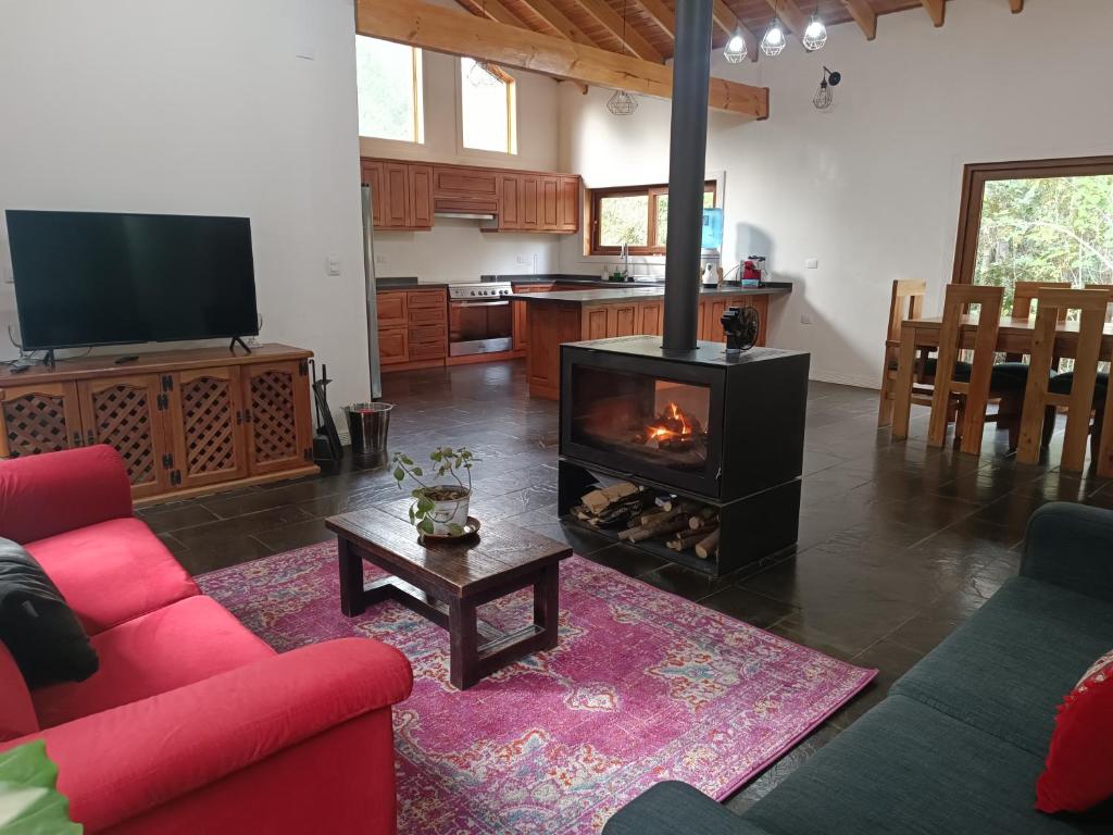 ein Wohnzimmer mit einem roten Sofa und einem Kamin in der Unterkunft Casa con quincho y piscina privados in Recinto
