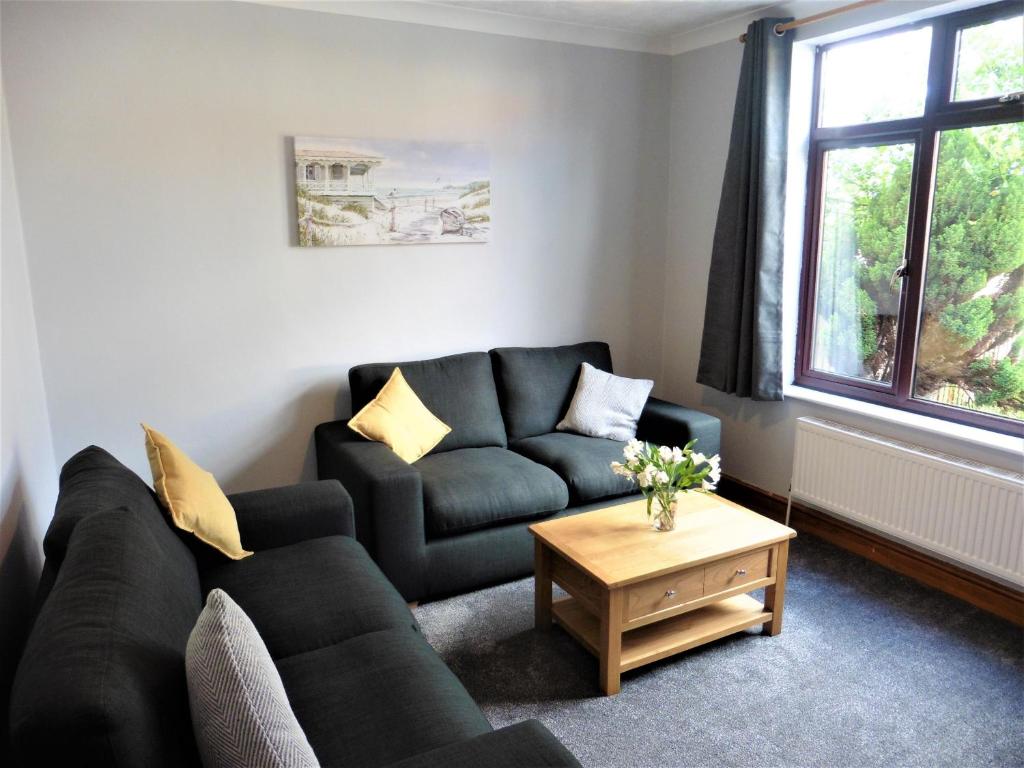 a living room with a black couch and a table at 3BD House Minutes from Great Yarmouth Seaside in Great Yarmouth