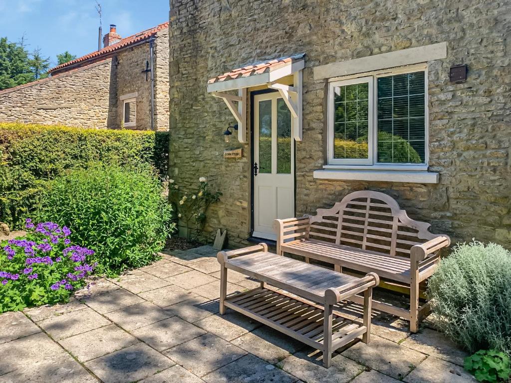 una casa de piedra con un banco y una puerta en Corn Stook - 16867 en Sawdon