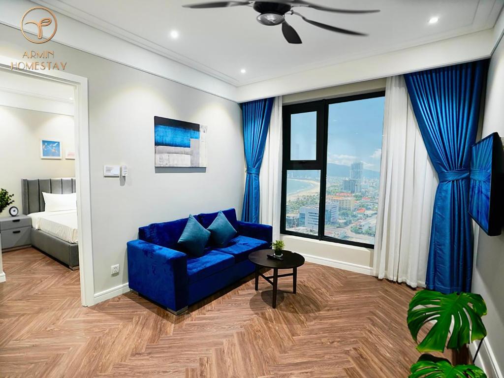 ein Wohnzimmer mit einem blauen Sofa vor einem Fenster in der Unterkunft Armin Homes Altara Residences Quy Nhon in Quy Nhon
