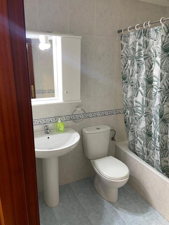 Un baño con inodoro, lavabo y espejo. en Cangas Piso Completo, en Cangas de Morrazo