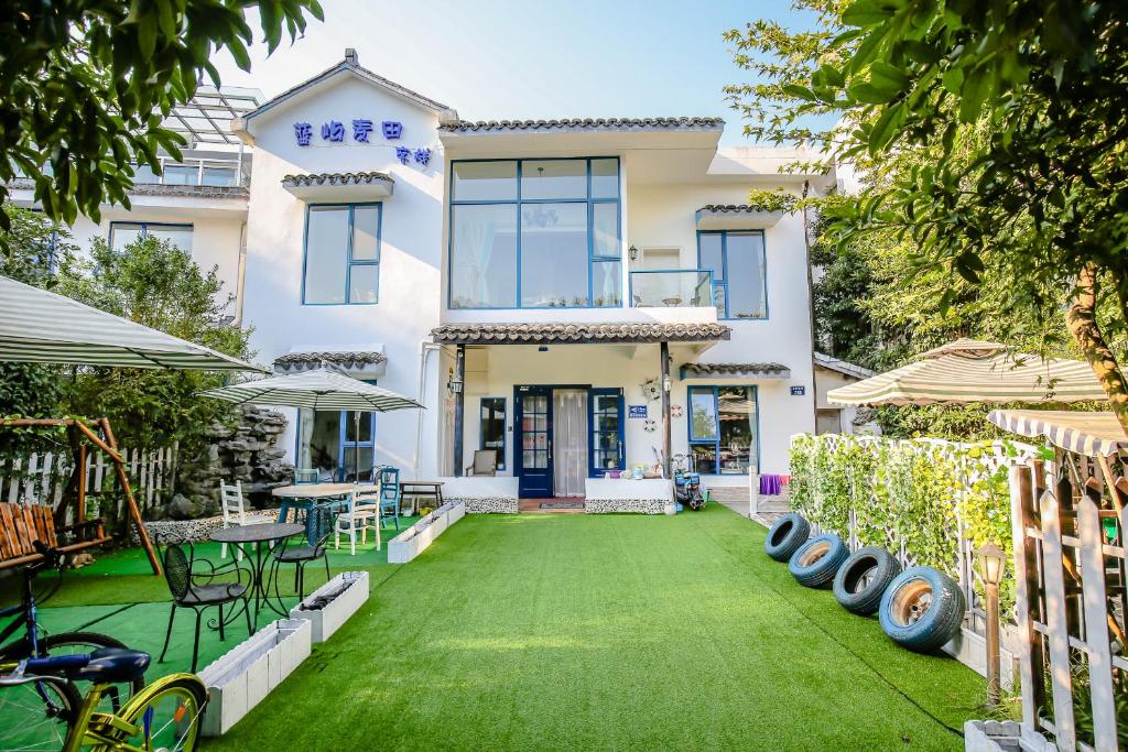 una casa con un prato verde davanti di Gala Seeker INN a Hangzhou