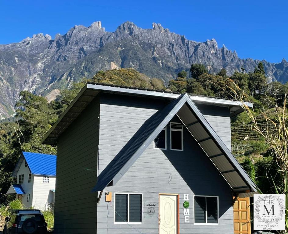 ein Haus mit einem Berg im Hintergrund in der Unterkunft The M Wanderlust Private Cabin in Ranau