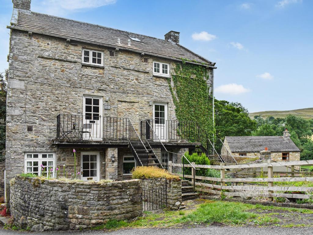 an old stone house with ivy on the side of it at 1 The Old Corn Mill in Middleham