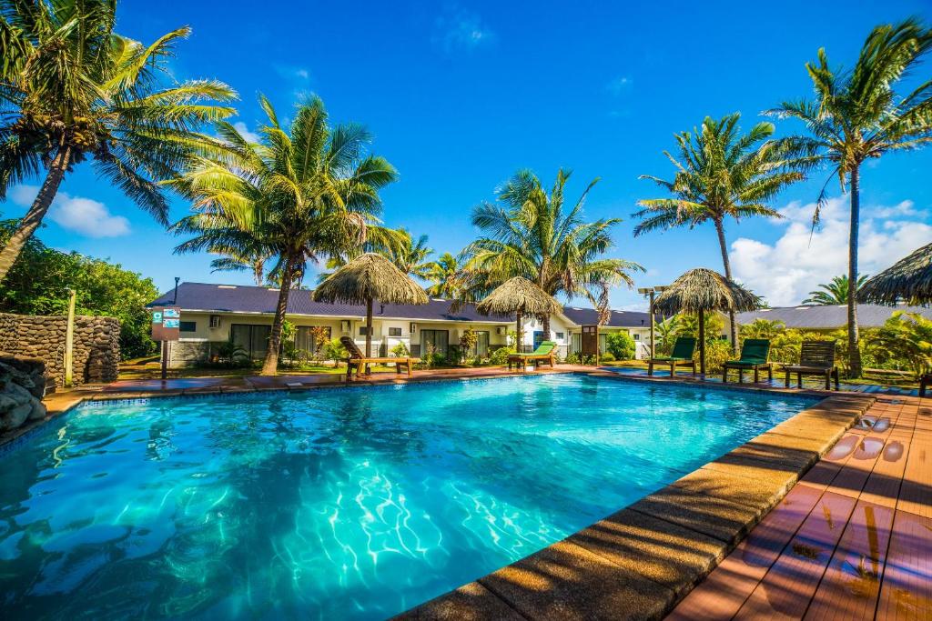 a swimming pool with palm trees and a house at Taha Tai in Hanga Roa