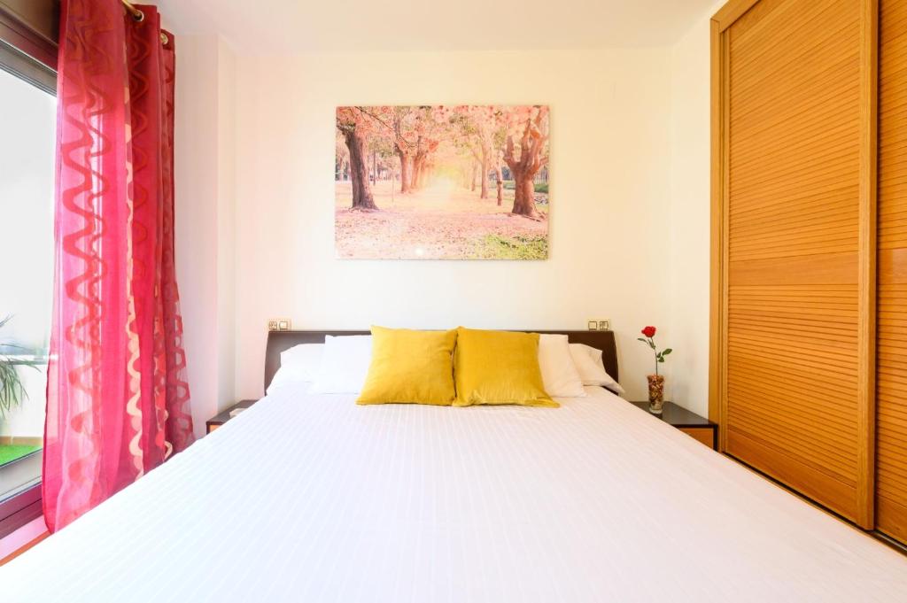 sypialnia z dużym łóżkiem z żółtymi poduszkami w obiekcie Apartamento Litoral Blue w Maladze