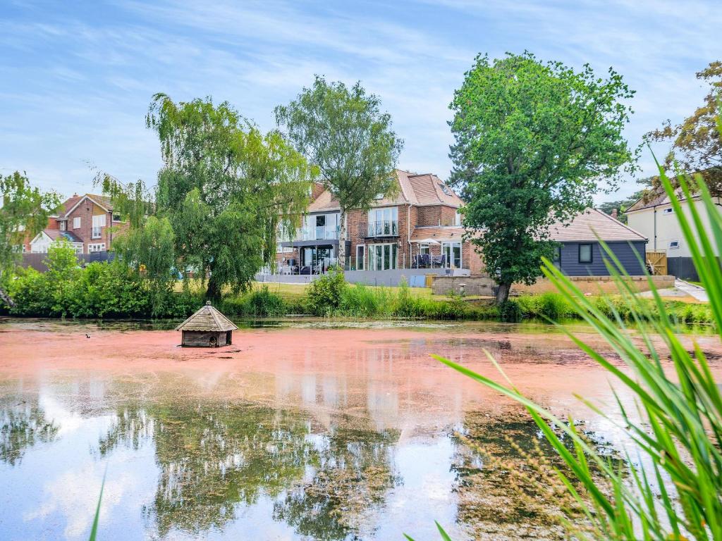 a house is reflected in the water of a pond at Still Waters in Hill Head