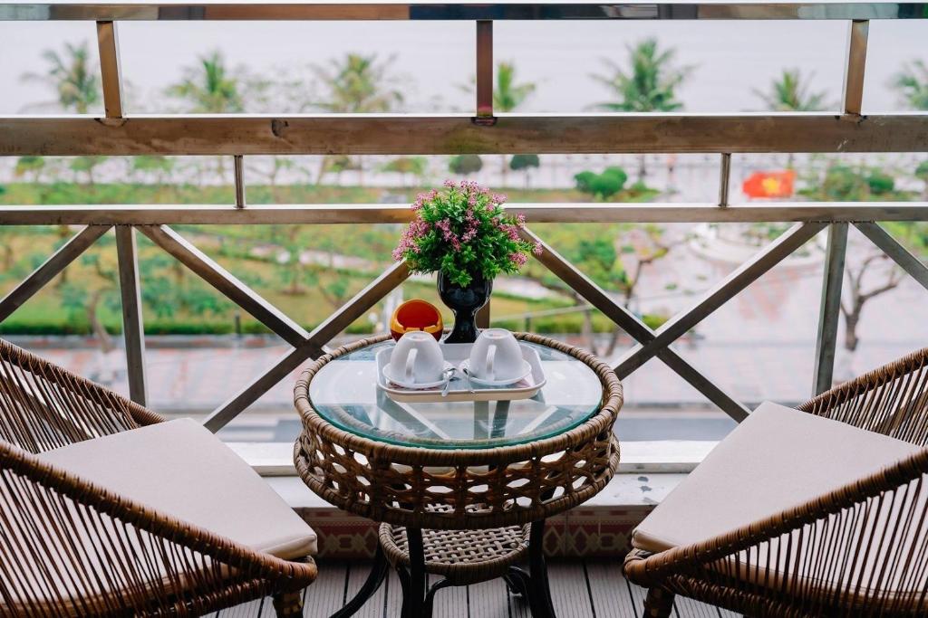 una mesa con un jarrón de flores en el balcón en Gia Cat Long Hotel, en Cat Ba