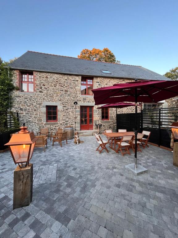 a patio with a table and an umbrella and a dog at Domaine du tertre ychot in Dol-de-Bretagne