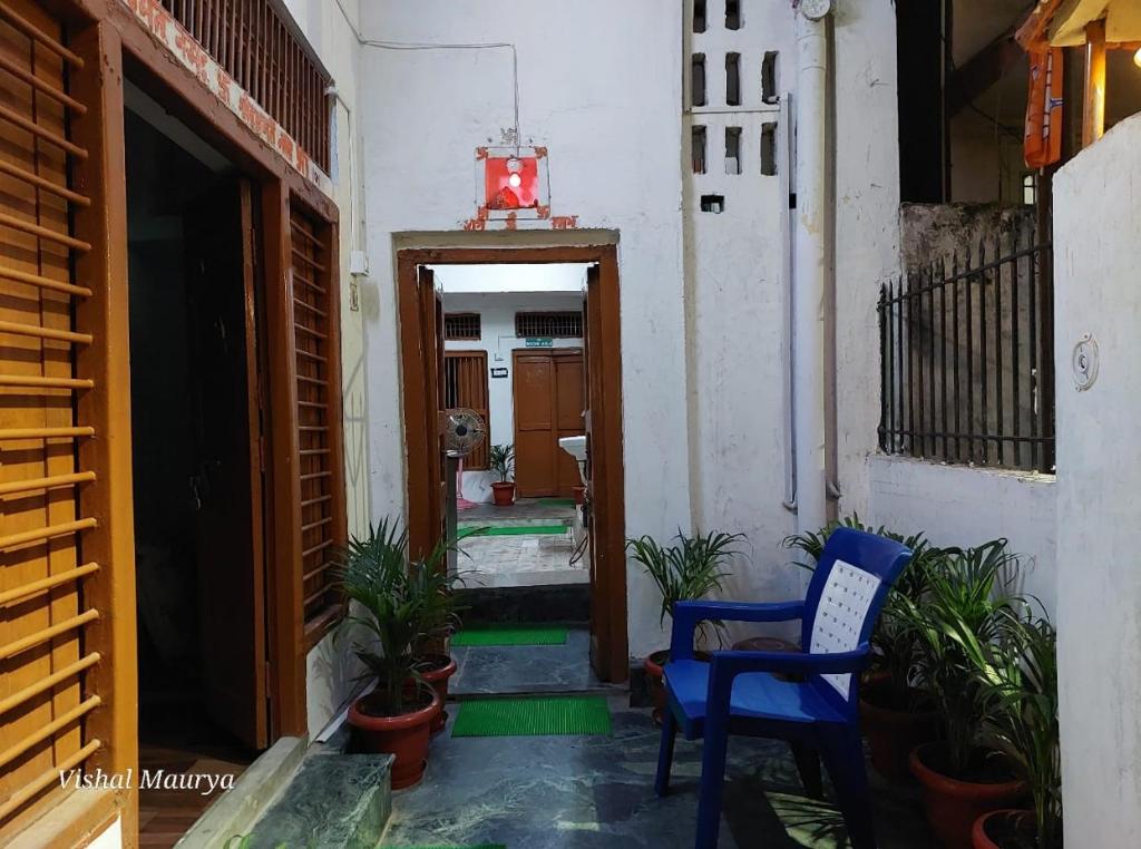 a hallway with a blue chair and some plants at Maa Tara AC Home Stay in Varanasi