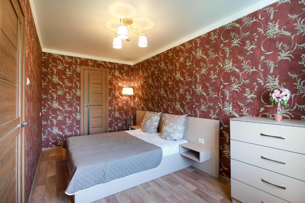 a small bedroom with a bed and red wallpaper at Двушка люкс автовокзал in Mykolaiv