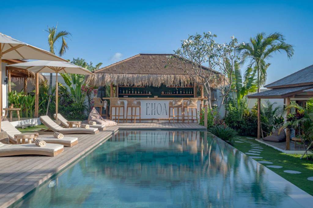 a resort pool with lounge chairs and a building at EHOA BALI Nyanyi Boutique Hotel - In front of entrance to NUANU in Tanah Lot