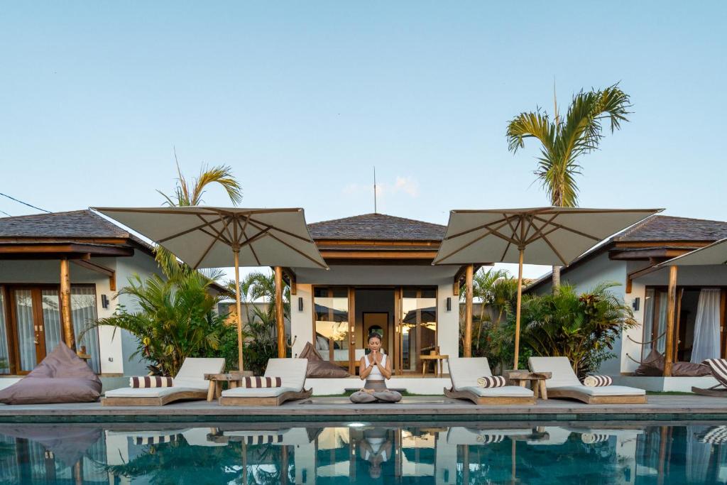 a person sitting on a chair next to a swimming pool at EHOA BALI Nyanyi Boutique Hotel - In front of entrance to NUANU in Tanah Lot