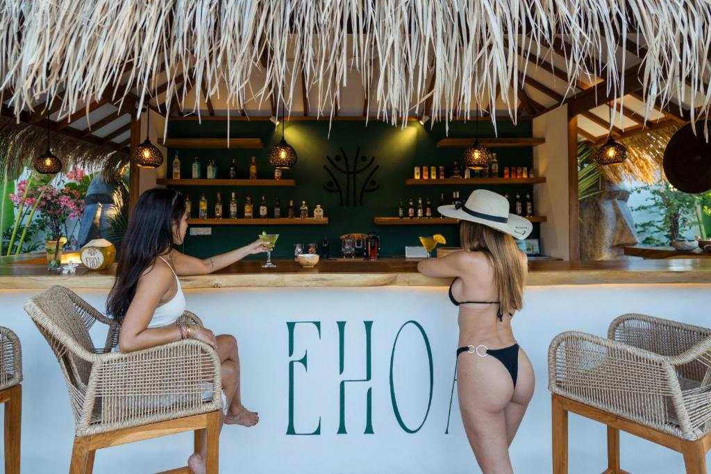 two women in bikinis sitting at a bar at EHOA BALI Nyanyi Boutique Hotel - In front of entrance to NUANU in Tanah Lot