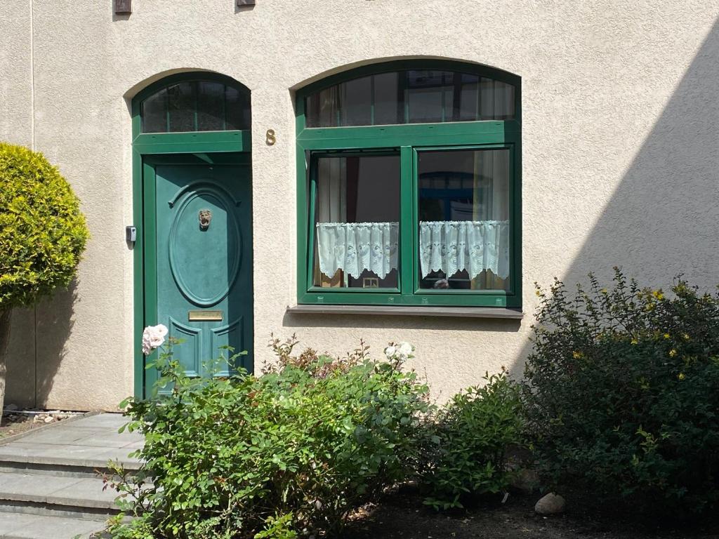 a house with a green door and a window with curtains at Kauris Apartament in Gdańsk
