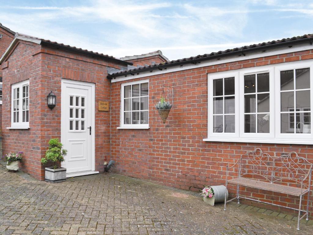 a brick house with a bench and a white door at Belvoir Lodge - Uk44743 in Tetford