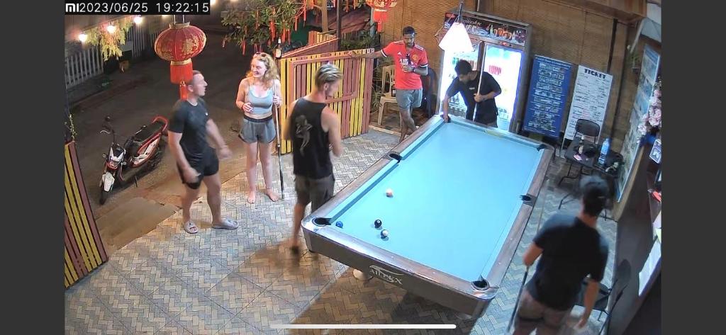 a group of people standing around a pool table at DownTown Backpackers Hostel in Luang Prabang
