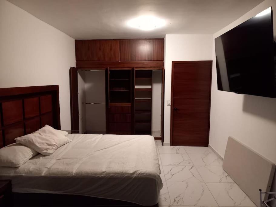 um quarto com uma cama e uma televisão em apartamento a 15 mins del centro em Tepic