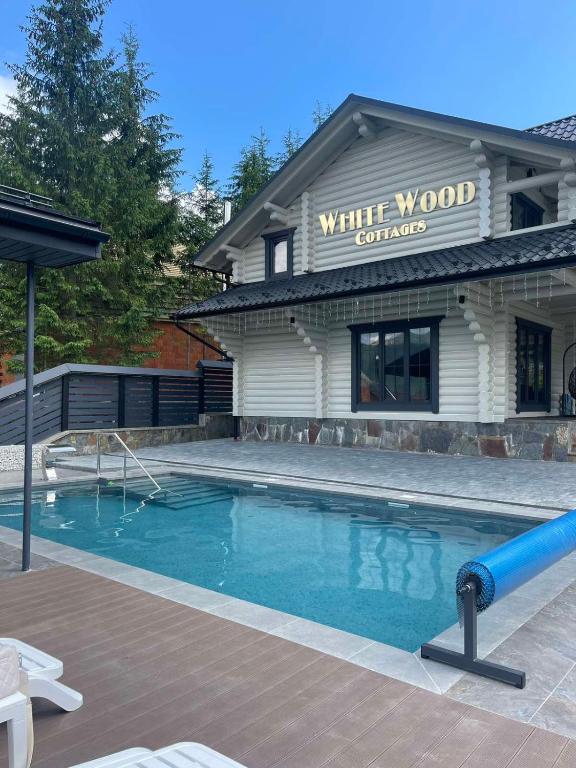a swimming pool in front of a building at WhiteWood Cottages in Bukovel