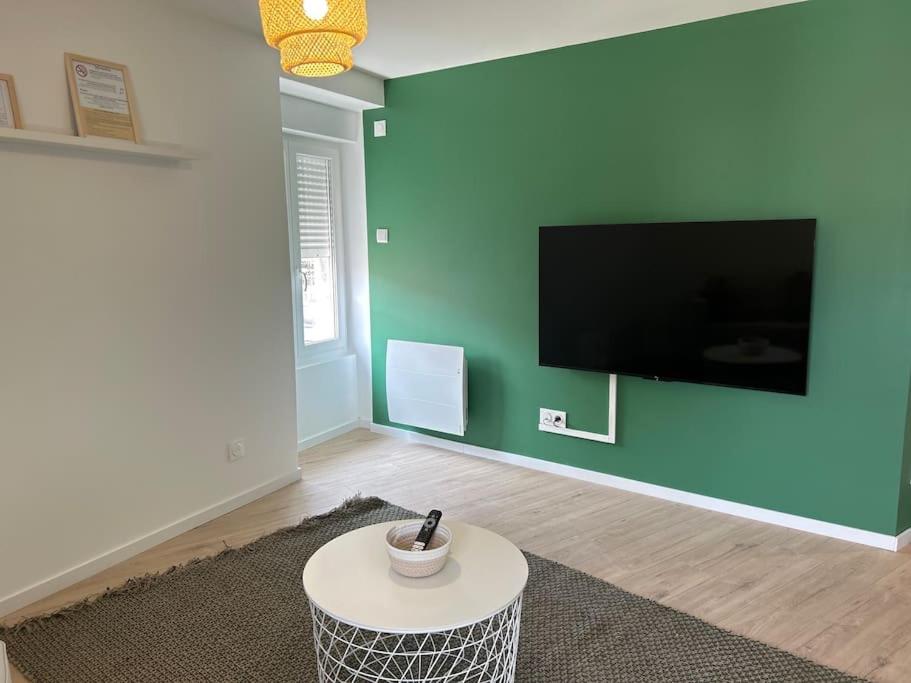 un soggiorno con parete verde e TV di Appart le 201 Jasseron a Jasseron