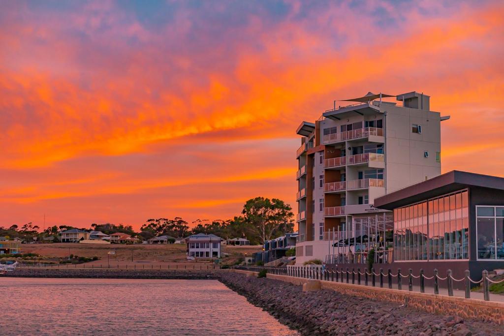 a building next to a body of water with a sunset at Wallaroo Marina Apartments in Wallaroo