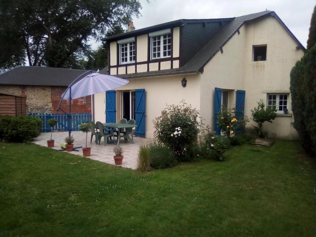 uma casa branca com um guarda-chuva no quintal em MAISON DU CLOCHER em Le Planquay