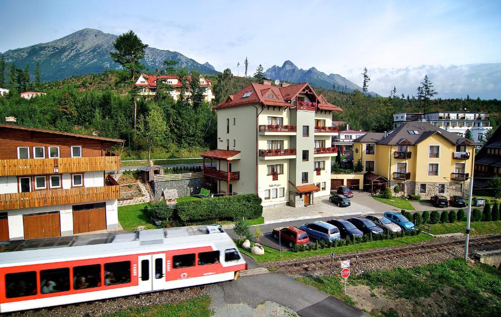 a train on the tracks in a town with buildings at Villa Krejza in Vysoke Tatry - Horny Smokovec